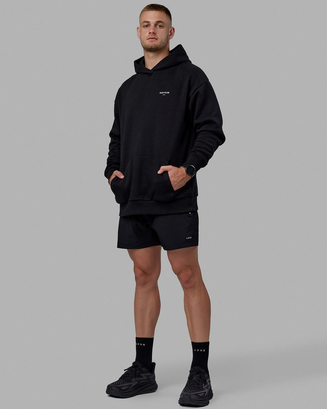 Man wearing Unisex RUN-CLUB Hoodie Oversize - Black