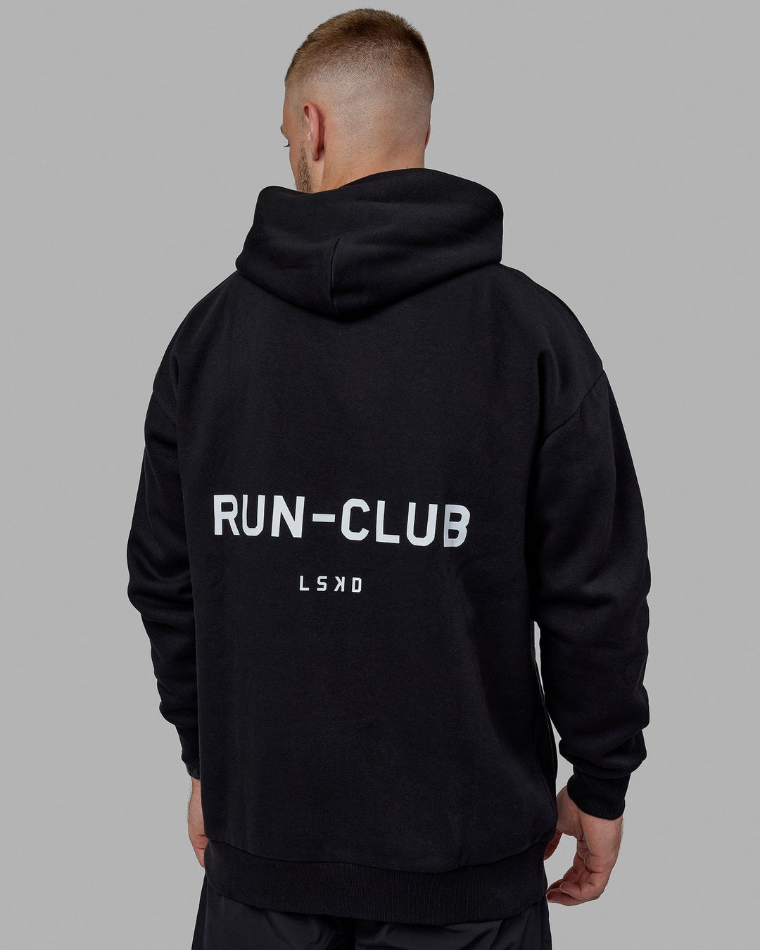 Man wearing Unisex RUN-CLUB Hoodie Oversize - Black