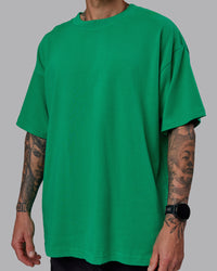Man wearing Unisex We Rise Heavyweight Tee Oversize - Impact Green-White