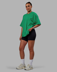 Woman wearing Unisex We Rise Heavyweight Tee Oversize - Impact Green-White