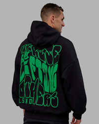 Man wearing Unisex We Rise Hoodie Oversize - Black-Impact Green