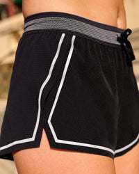 Woman wearing Accelerate 3" Reflective Mid-Rise Running Short - Black-Reflective | Model:Em | Size:S