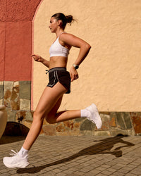 Woman wearing Accelerate 3" Reflective Mid-Rise Running Short - Black-Reflective | Model:Em | Size:S