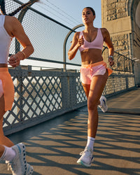 Woman wearing Accelerate 3" Mid-Rise Running Short - Cantaloupe-Marshmallow | Model:Olivia | Size:S