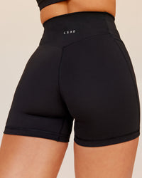 Woman wearing Fusion V-Contour Ultra High-Rise 4” Short Pockets - Black | Model:Shae | Size:S