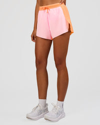 Woman wearing Accelerate 3" High-Rise Running Short - Cantaloupe-Marshmallow | Set:true | Angle:side | Model:Ruby | Size:S