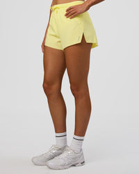 Woman wearing Accelerate 3" High-Rise Running Short - Yellow Fizz | Set:true | Angle:side | Model:Evie | Size:S