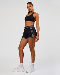 Woman wearing Accelerate 3" Reflective High-Rise Running Short - Black-Reflective | Model:Rosie | Size:S
