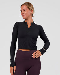 Woman wearing AeroFLX+ Long Sleeve Skimmer Half Zip - Black Marl | Model:Amity | Size:S