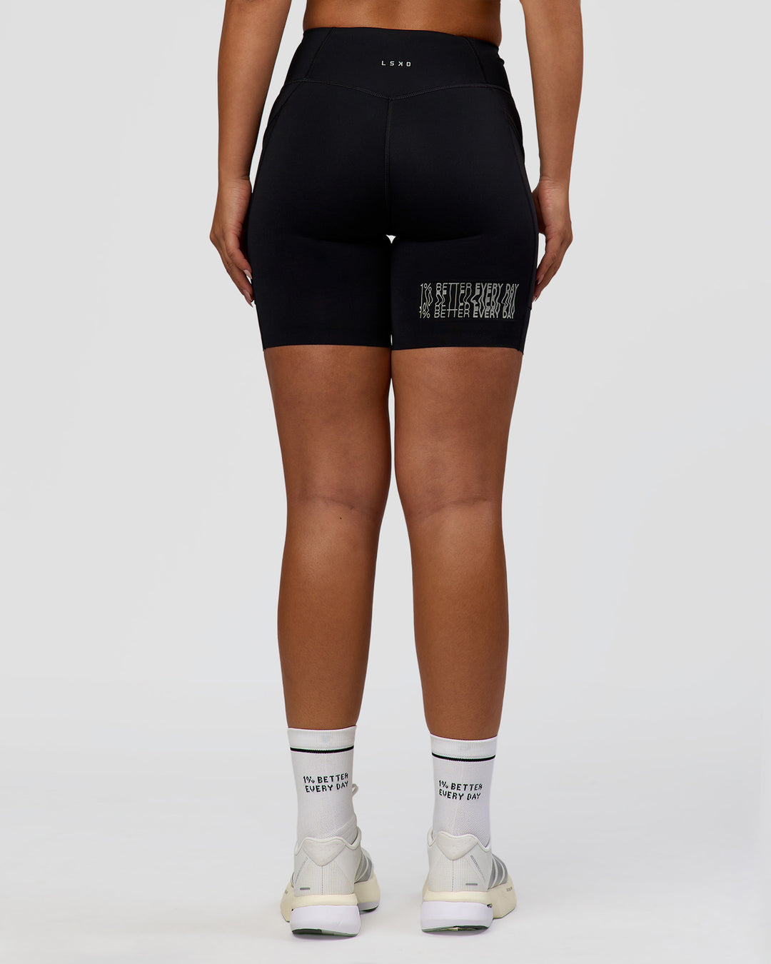 Woman wearing Elite Hype Reflective Run High-Rise 7" Short Pockets - Black-Hype Reflective | Model:Sophia | Size:S
