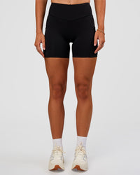 Woman wearing Elite Run High-Rise 5" Short Pockets - Black | Model:Emelia | Size:S