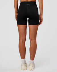 Woman wearing Elite Run High-Rise 5" Short Pockets - Black | Model:Emelia | Size:S