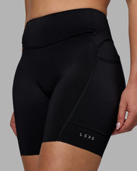 Woman wearing Elite Run High-Rise 7" Short Pockets - Black | Model:Charlize | Size:S