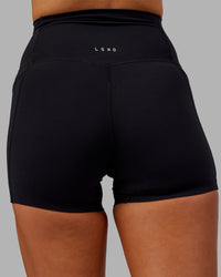Woman wearing Elixir Ultra High-Rise 4" Short Pockets - Black | Model:Kirstyn | Size:S