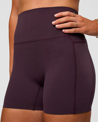 Woman wearing Elixir Ultra High-Rise 4" Short Pockets - Midnight Plum | Model:Emelia | Size:S