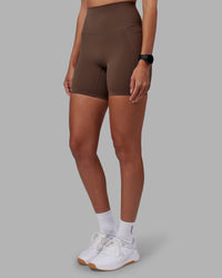 Woman wearing Elixir Ultra High-Rise 6" Short Pockets - Chocolate Martini | Model:Rhiley | Size:S