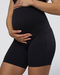 Woman wearing Elixir Ultra High-Rise Maternity 6" Short Pockets - Black | Model:Kitahna | Size:S