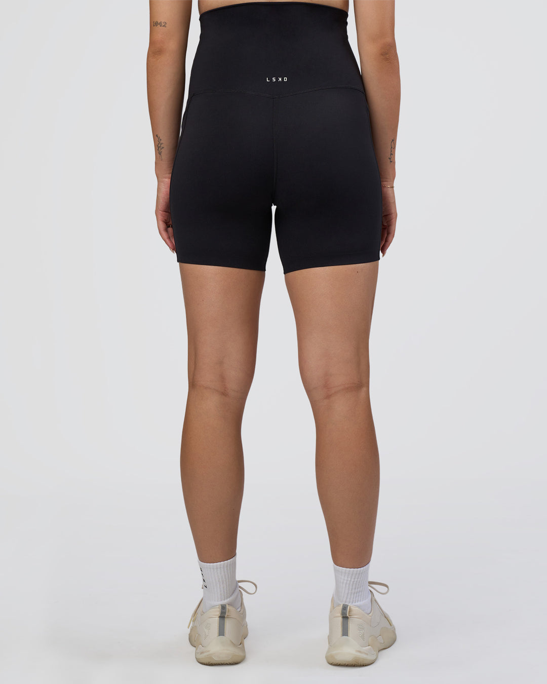 Woman wearing Elixir Ultra High-Rise Maternity 6&quot; Short Pockets - Black | Model:Kitahna | Size:S