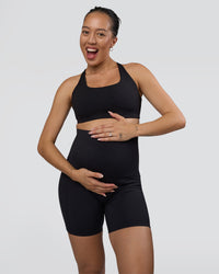 Woman wearing Elixir Ultra High-Rise Maternity 6" Short Pockets - Black | Model:Kitahna | Size:S