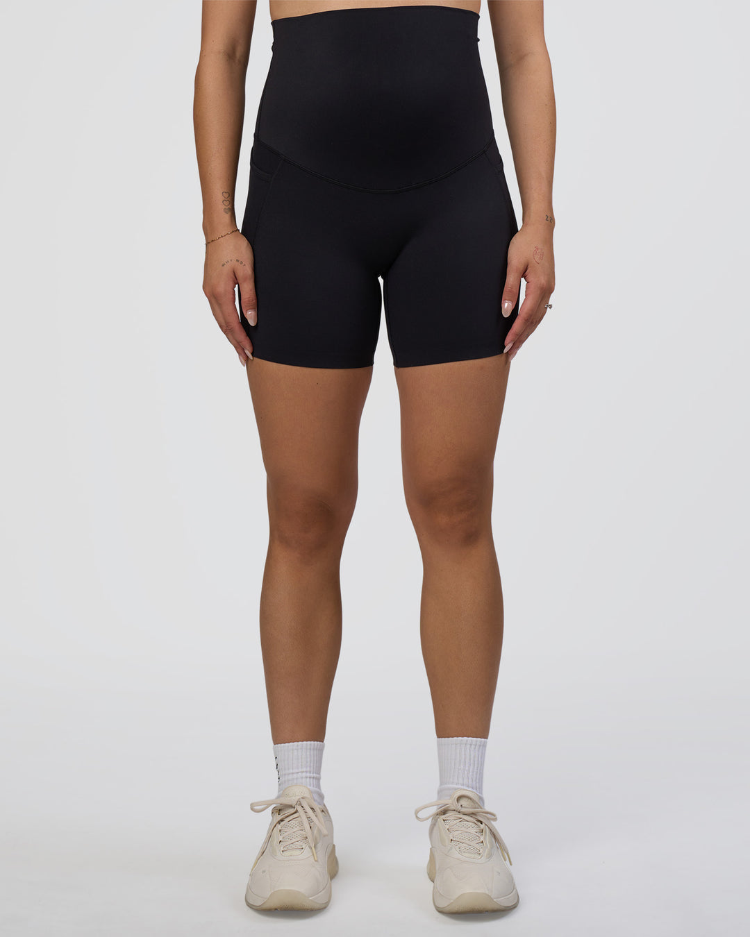Woman wearing Elixir Ultra High-Rise Maternity 6&quot; Short Pockets - Black | Model:Kitahna | Size:S
