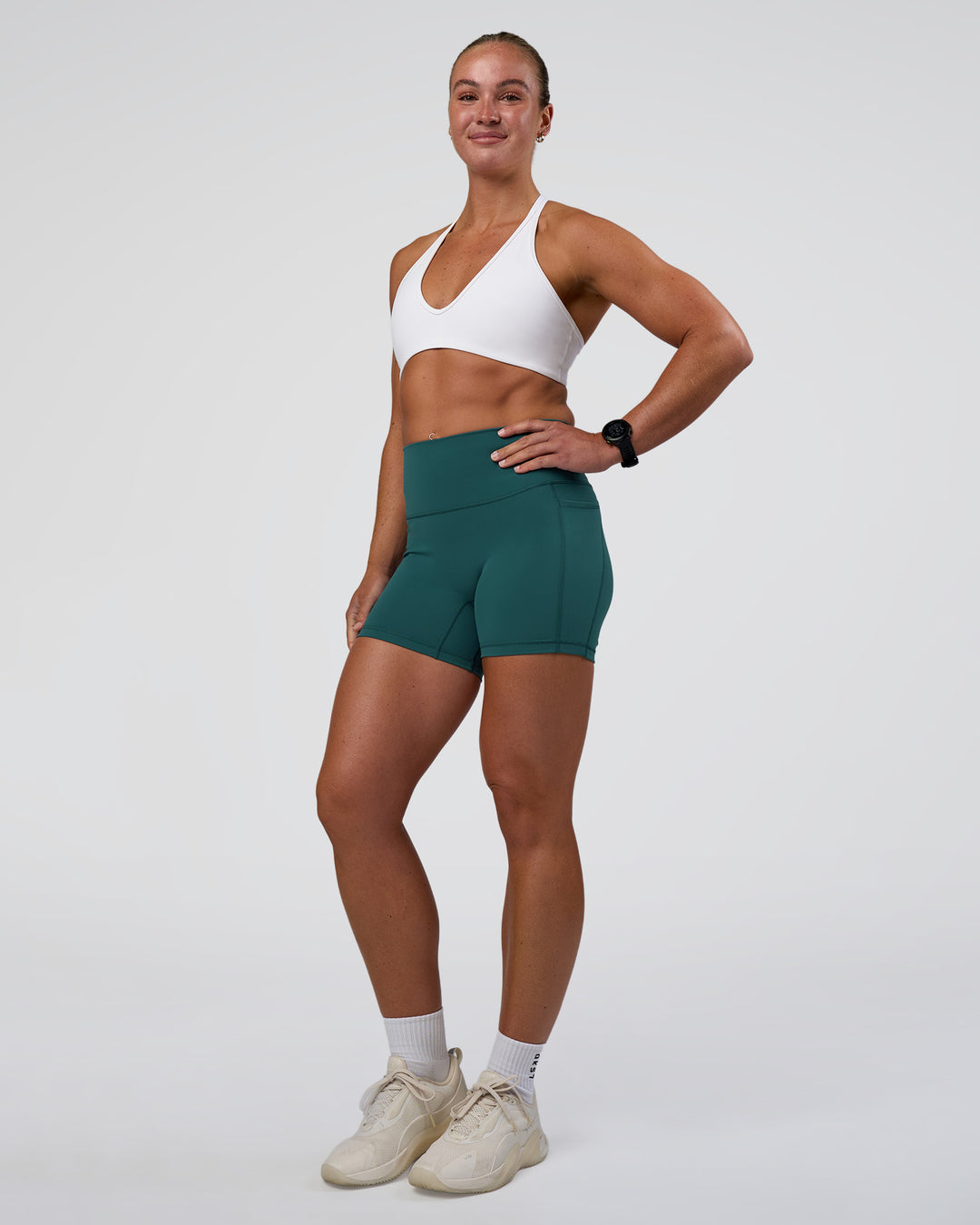 Woman wearing Fusion High-Rise 4" Short Pockets - Transformative Teal | Model:Sav | Size:S