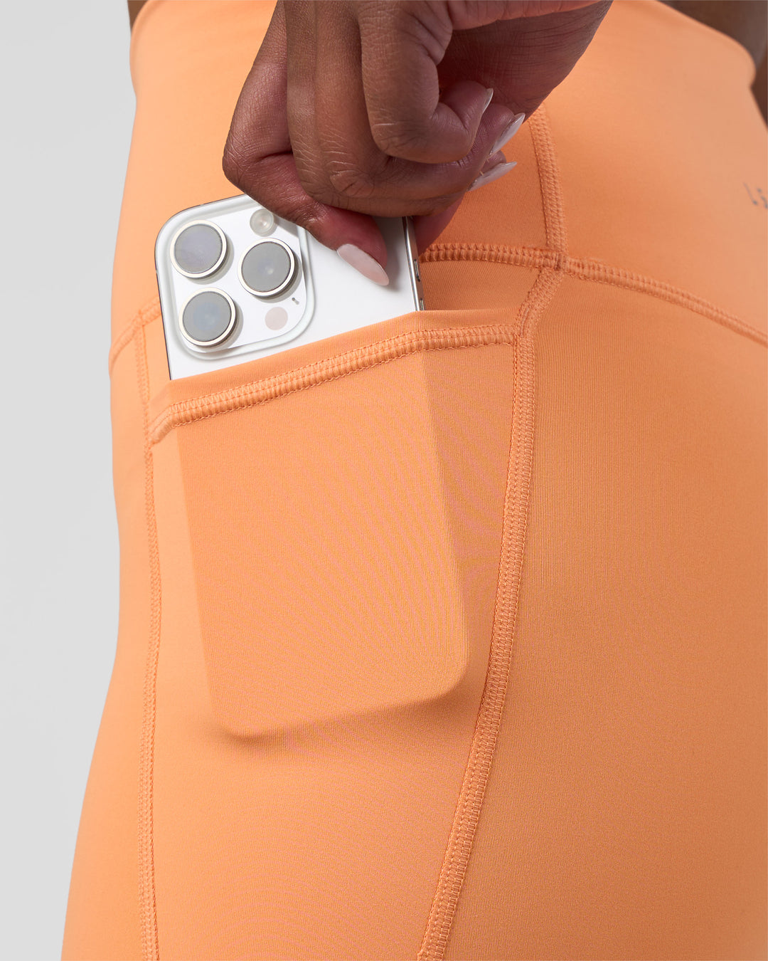 Woman wearing Fusion Ultra High-Rise 4&quot; Short Pockets - Cantaloupe | Model:Rica | Size:S