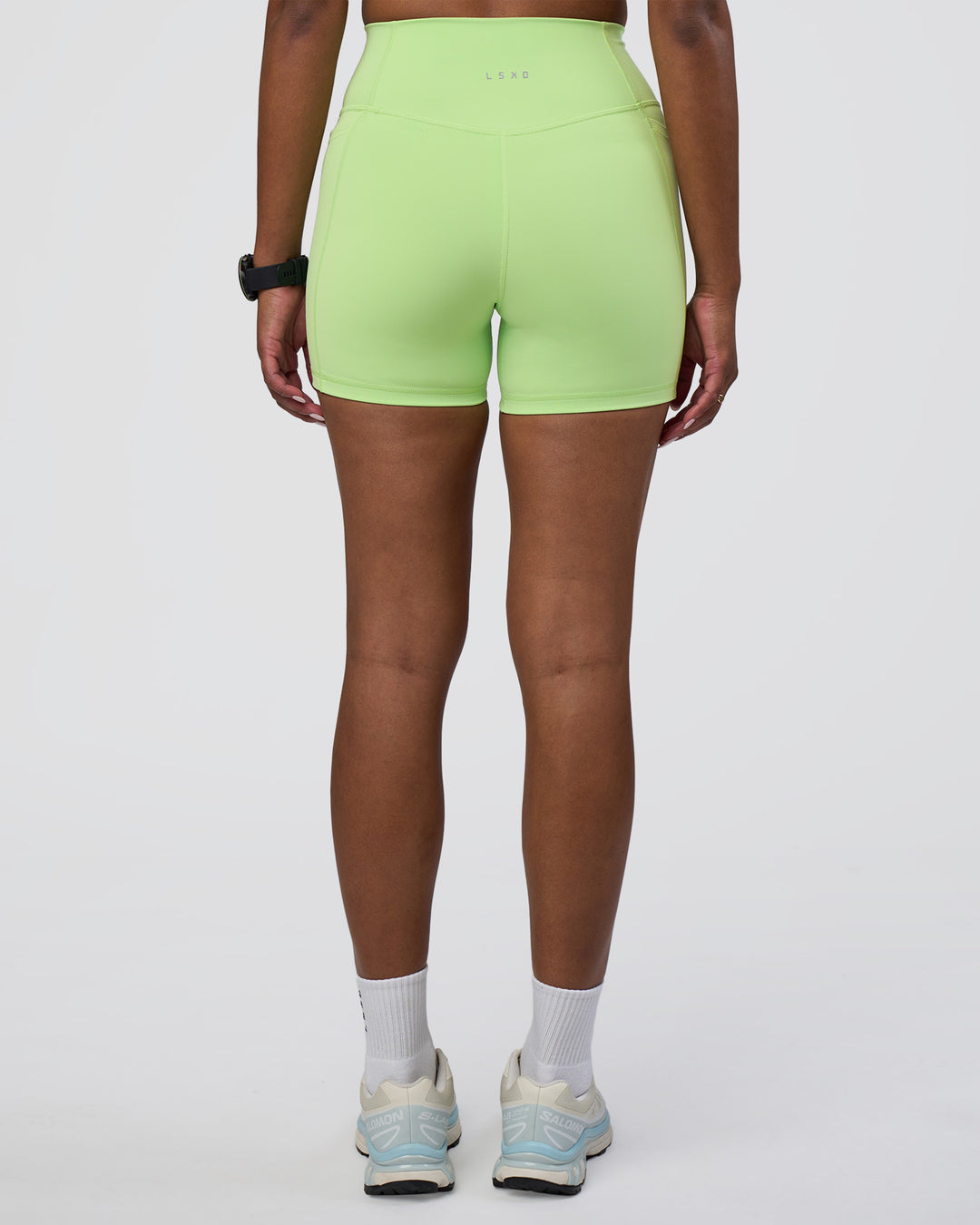 Woman wearing Fusion Ultra High-Rise 4&quot; Short Pockets - Solar Lime | Model:Rica | Size:S
