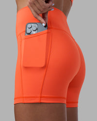 Woman wearing Fusion Ultra High-Rise 4" Short Pockets - Ultra Orange | Set:true | Angle:closeup | Model:Katie | Size:S
