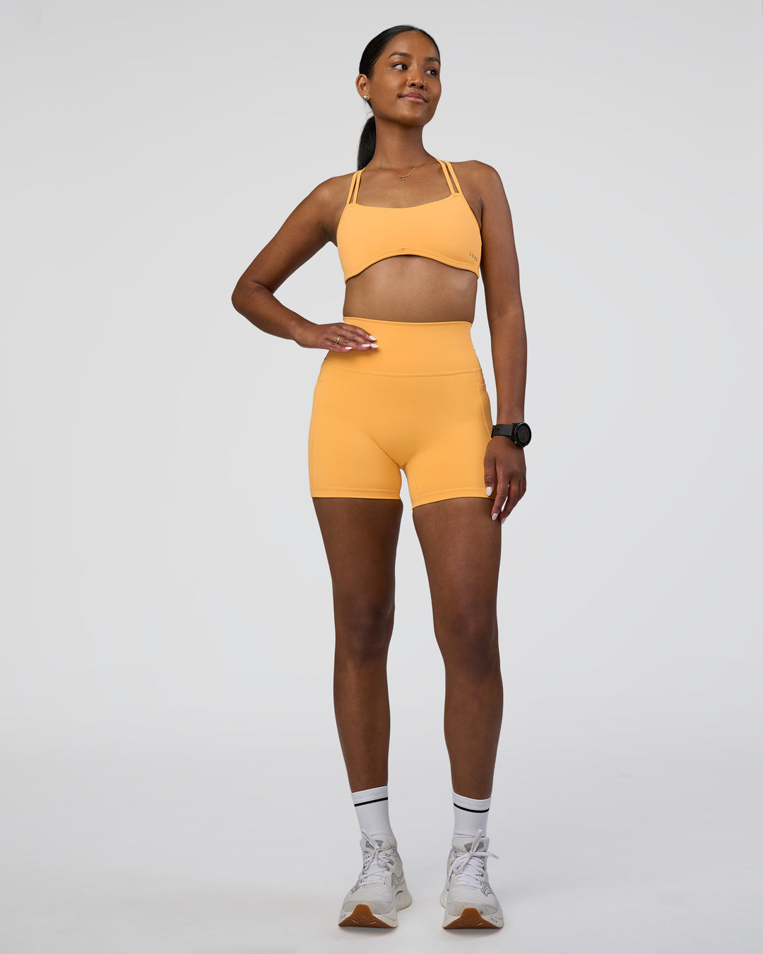 Woman wearing Fusion Ultra High-Rise 4&quot; Short Pockets - Warm Apricot | Model:Rica | Size:S