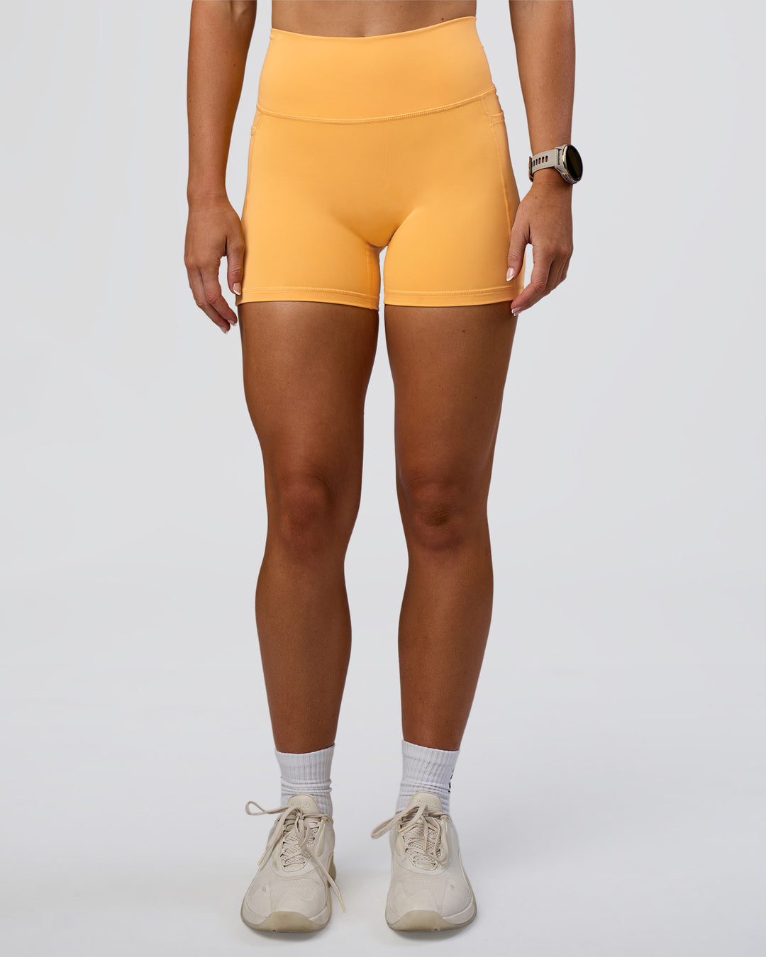 Woman wearing Fusion Ultra High-Rise 4" Short Pockets - Warm Apricot | Model:Emelia | Size:S