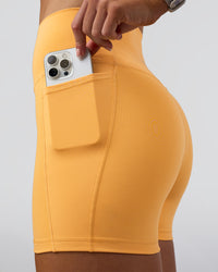Woman wearing Fusion Ultra High-Rise 4" Short Pockets - Warm Apricot | Set:true | Angle:closeup | Model:Emelia | Size:S