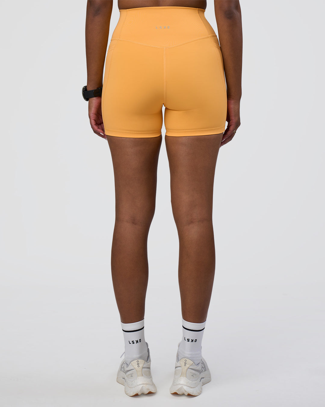 Woman wearing Fusion Ultra High-Rise 4&quot; Short Pockets - Warm Apricot | Model:Rica | Size:S