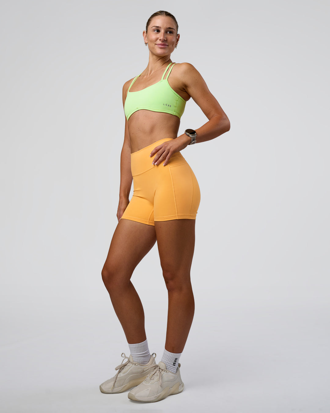 Woman wearing Fusion Ultra High-Rise 4" Short Pockets - Warm Apricot | Model:Emelia | Size:S