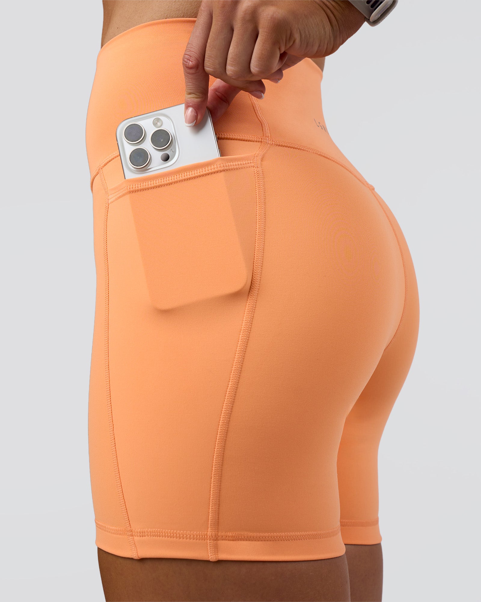 Woman wearing Fusion Ultra High-Rise 6" Short Pockets - Cantaloupe | Model:Emelia | Size:S