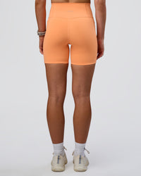 Woman wearing Fusion Ultra High-Rise 6" Short Pockets - Cantaloupe | Set:true | Angle:back | Model:Emelia | Size:S