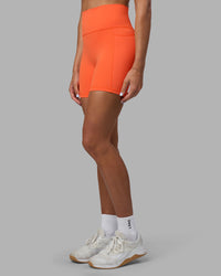 Woman wearing Fusion Ultra High-Rise 6" Short Pockets - Ultra Orange | Set:true | Angle:side | Model:Katie | Size:S