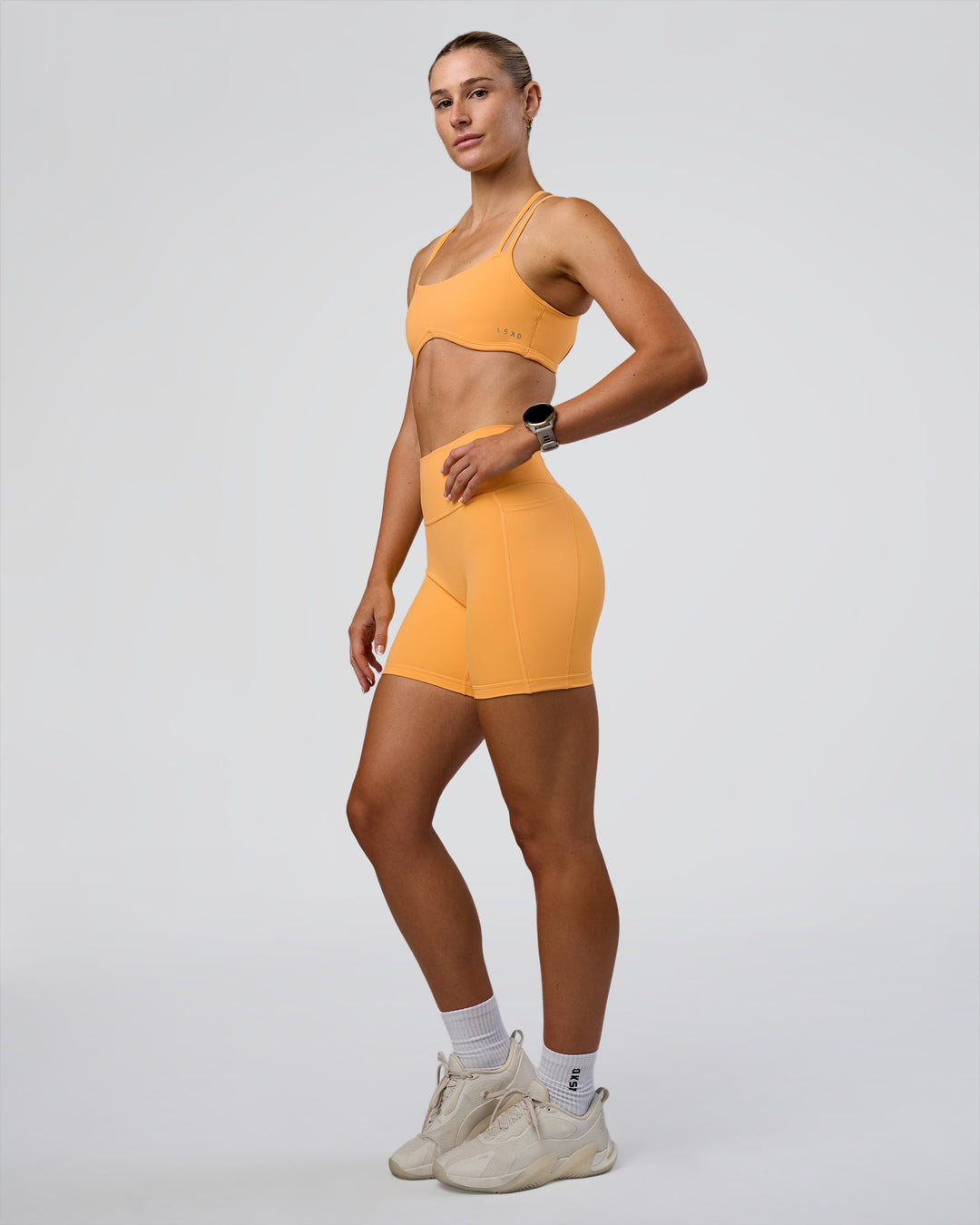 Woman wearing Fusion Ultra High-Rise 6" Short Pockets - Warm Apricot | Model:Emelia | Size:S