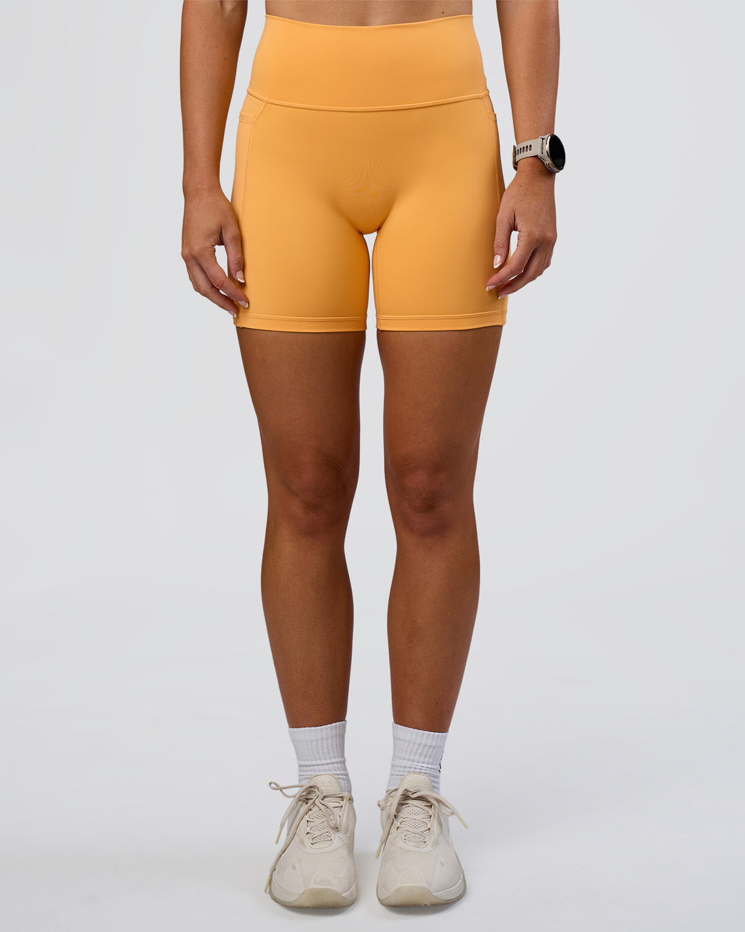 Woman wearing Fusion Ultra High-Rise 6" Short Pockets - Warm Apricot | Model:Emelia | Size:S