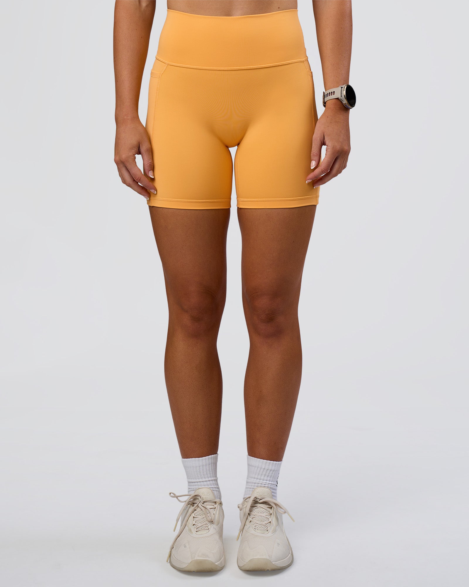 Woman wearing Fusion Ultra High-Rise 6" Short Pockets - Warm Apricot | Model:Emelia | Size:S