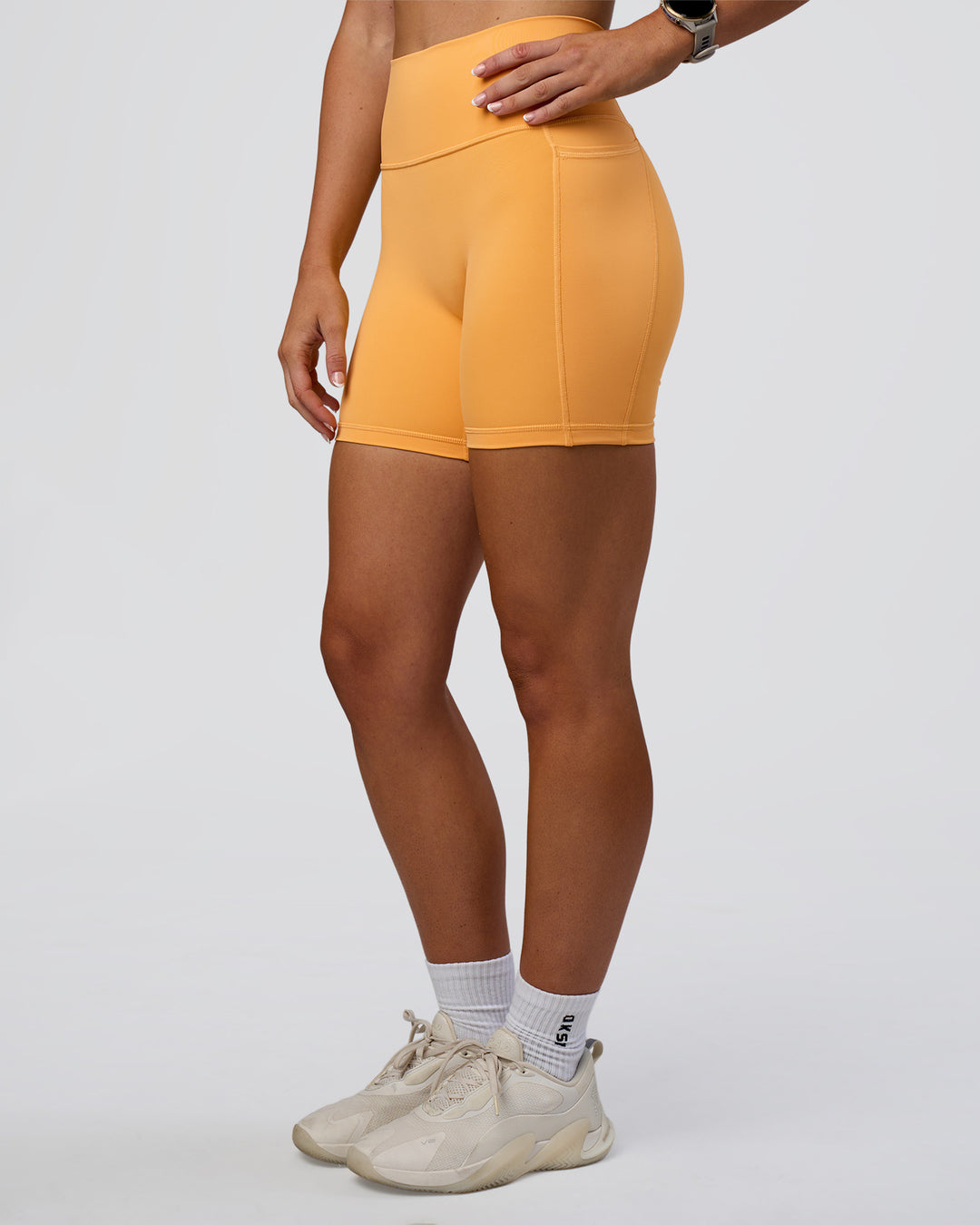 Woman wearing Fusion Ultra High-Rise 6" Short Pockets - Warm Apricot | Model:Emelia | Size:S
