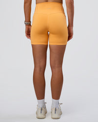 Woman wearing Fusion Ultra High-Rise 6" Short Pockets - Warm Apricot | Set:true | Angle:back | Model:Emelia | Size:S