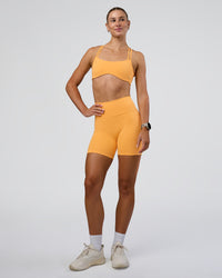 Woman wearing Fusion Ultra High-Rise 6" Short Pockets - Warm Apricot | Model:Emelia | Size:S
