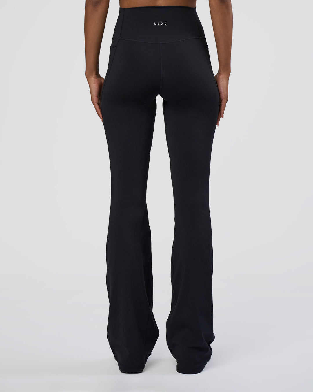 Woman wearing Fusion Ultra High-Rise Flared Tall Legging Pockets - Black | Model:Tomi | Size:S