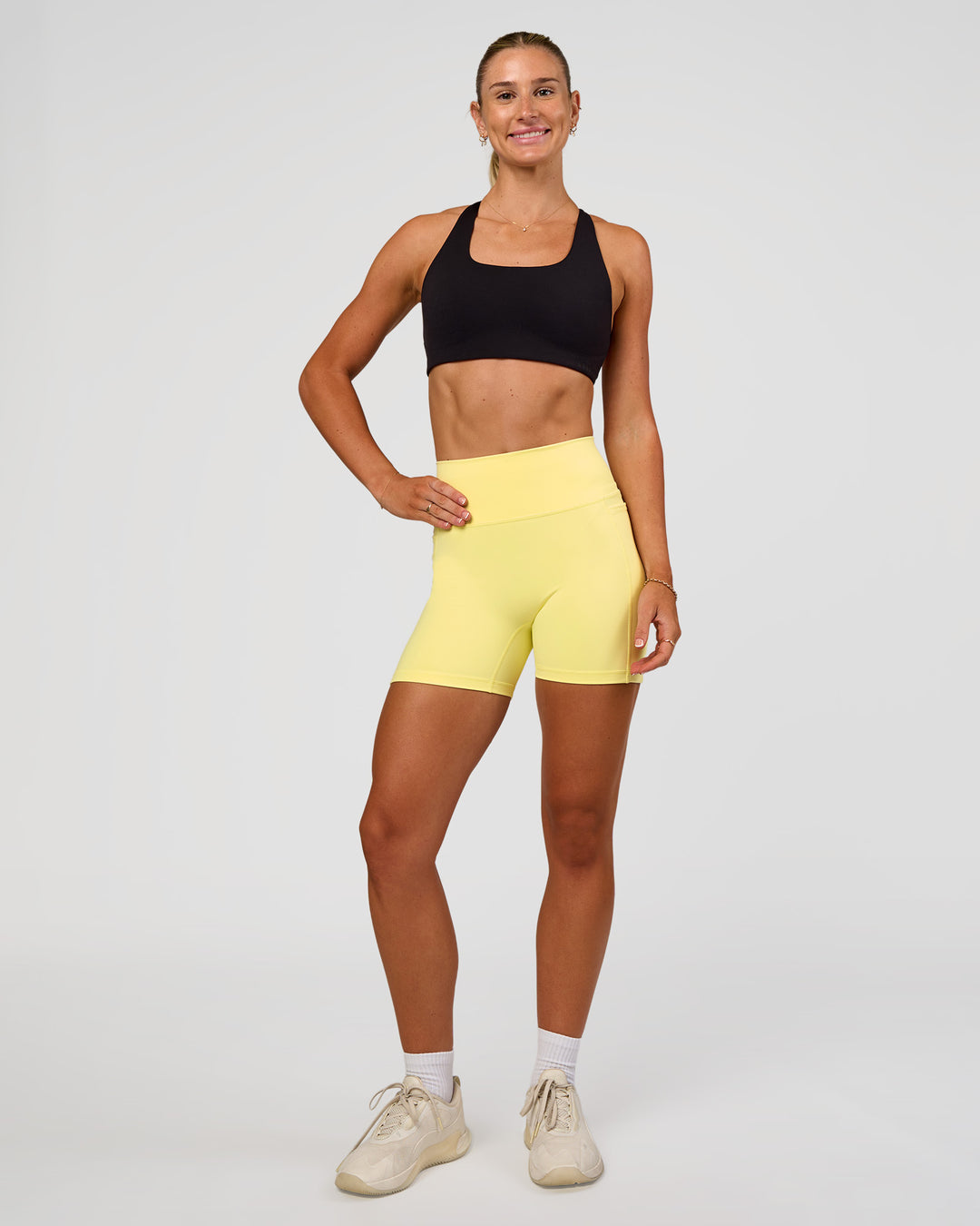 Woman wearing Fusion V-Contour Ultra High-Rise 4” Short Pockets - Yellow Fizz | Model:Emelia | Size:S