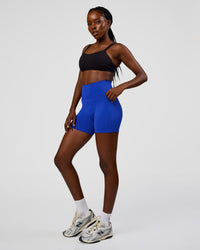 Woman wearing Fusion V-Contour Ultra High-Rise 4” Short Pockets - Electric Indigo | Model:Ellie | Size:S
