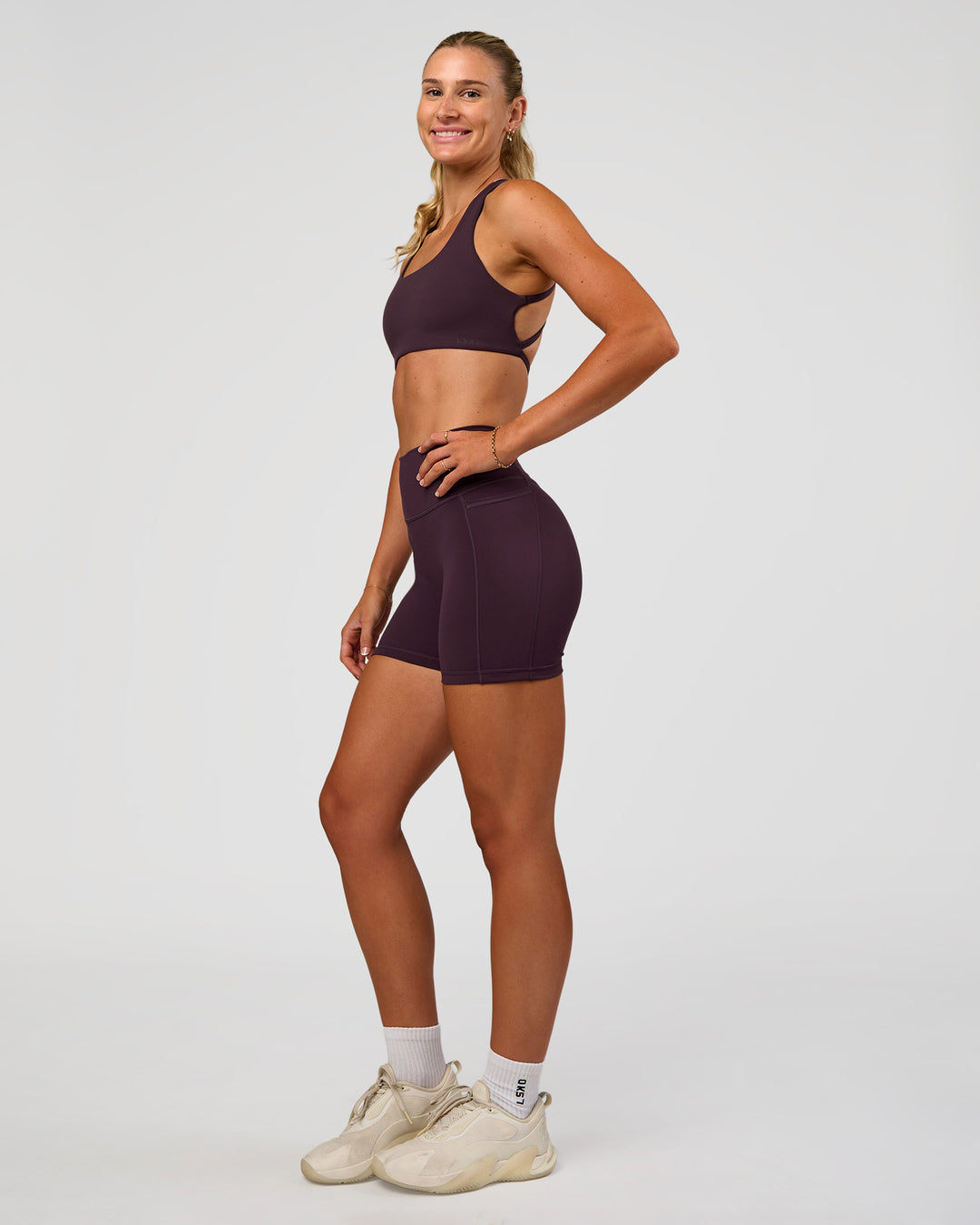 Woman wearing Fusion V-Contour Ultra High-Rise 4” Short Pockets - Midnight Plum | Model:Emelia | Size:S