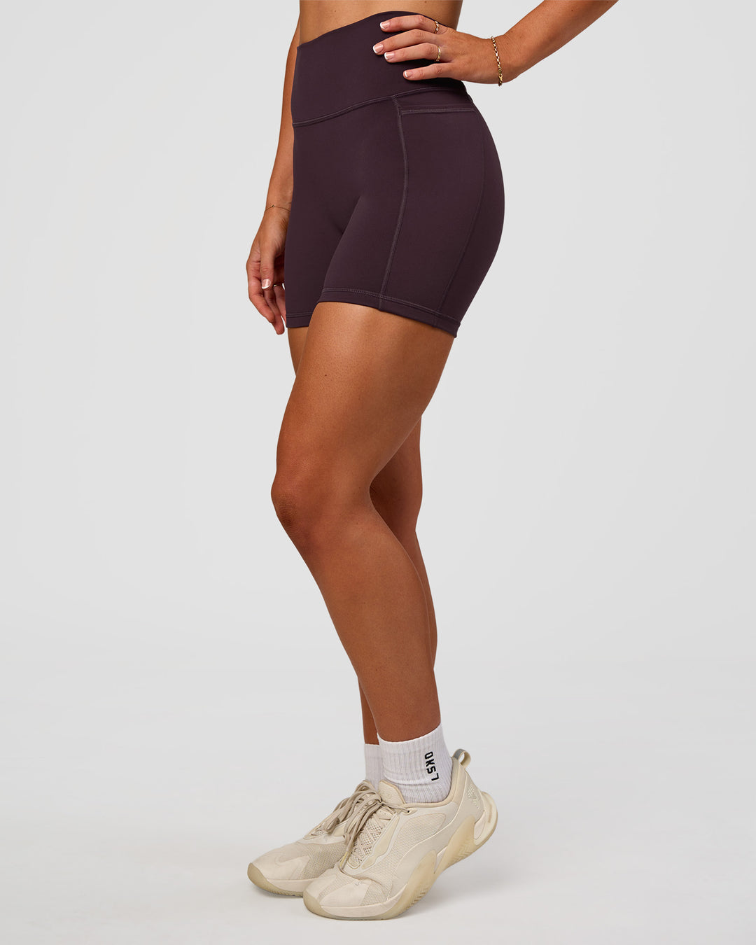 Woman wearing Fusion V-Contour Ultra High-Rise 4” Short Pockets - Midnight Plum | Model:Emelia | Size:S