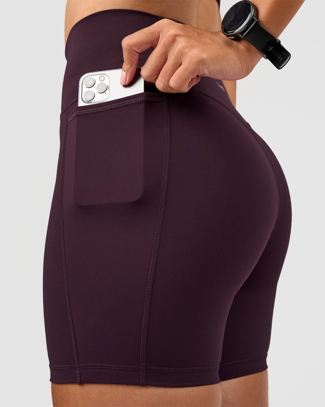 Woman wearing Fusion V-Contour Ultra High-Rise 6" Short Pockets - Midnight Plum | Model:Rhiley | Size:S