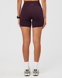 Woman wearing Fusion V-Contour Ultra High-Rise 6" Short Pockets - Midnight Plum | Model:Rhiley | Size:S