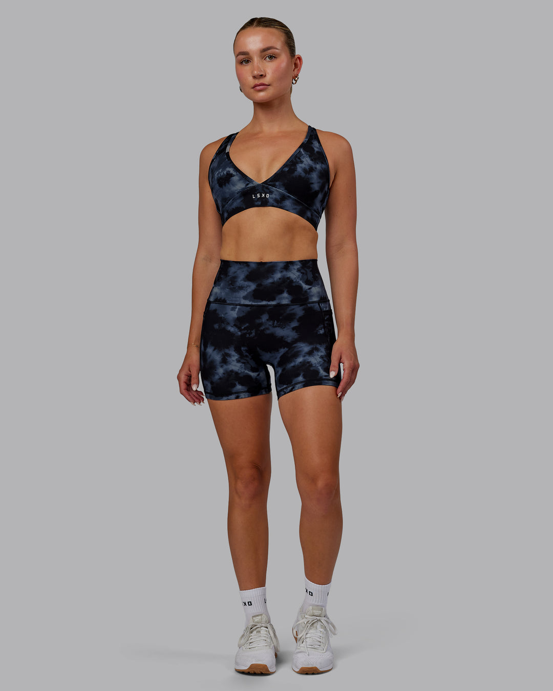 Woman wearing Fusion Ultra High-Rise 4&quot; Short Pockets - Tie Dye-Midnight | Model:Halle | Size:S